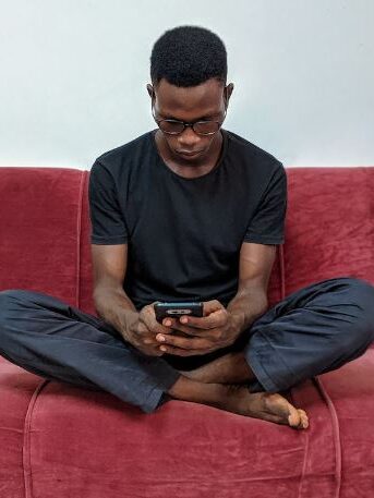 a man watching its smartphone on a couch