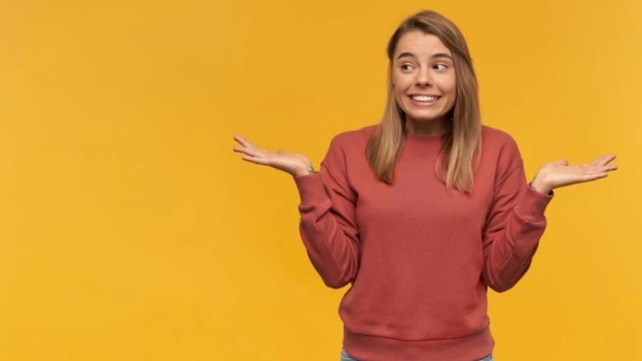 Person with a puzzled expression wearing a maroon sweatshirt, hands raised in a shrug.