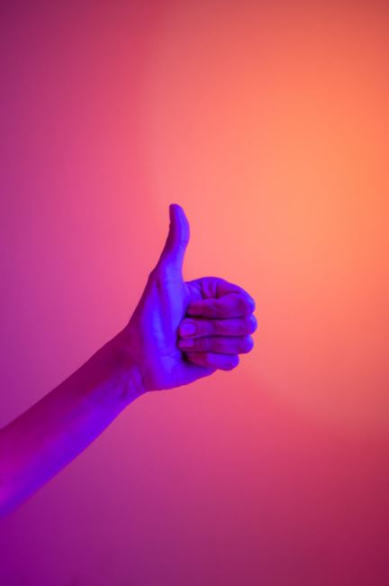 Hand giving a thumbs-up against a gradient background