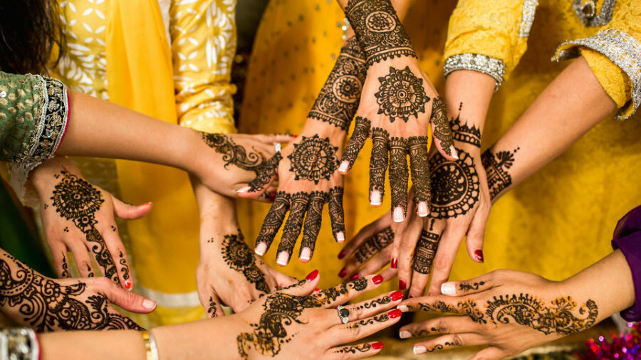 Close-up of hands with intricate henna patterns, showcasing traditional body art and festive attire.