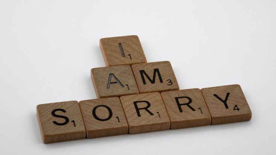 Wooden tiles spelling 'I am sorry' against a plain white backdrop.