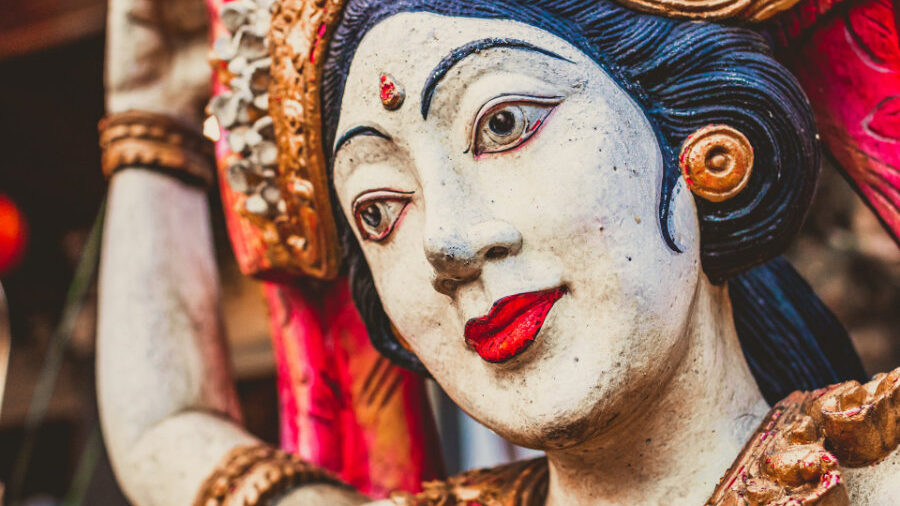 Close-up of a statue depicting a woman with red lips and traditional adornments, showcasing detailed artistry.