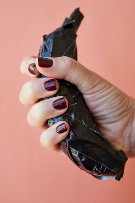 A manicured hand squeezing a banana-taped, with the focus on the painted nails and the tension in the grip.