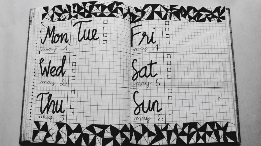 Black-and-white grid-style planner with checkboxes for each day, decorated with geometric designs.