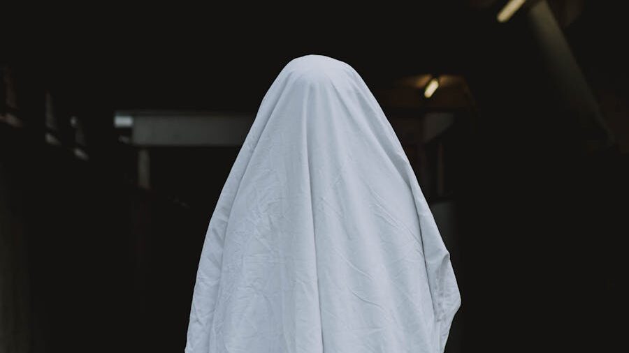 Person covered by a white sheet, resembling a classic ghost costume.