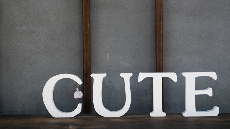 White decorative letters spelling “CUTE” on a wooden shelf, with a small pink plush toy hanging from the letter C.