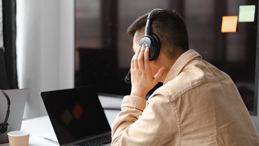 Person working indoors with a laptop and headphones, captured in a focused environment.