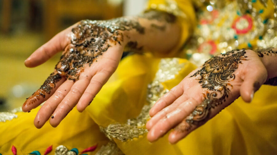 Mains avec des motifs détaillés au henné, symbolisant la célébration culturelle, tenues ouvertes avec les paumes tournées vers le haut.