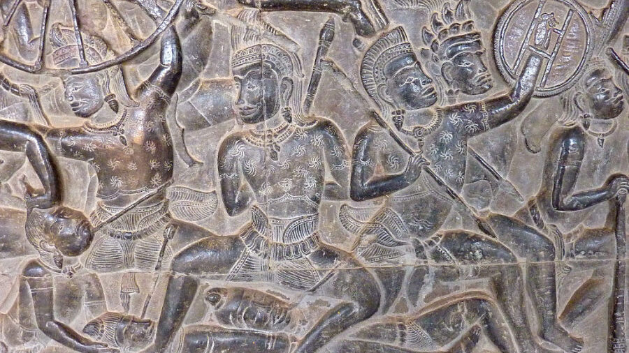 Relief en pierre représentant des guerriers du Mahabharata à Angkor Wat, avec des sculptures anciennes détaillées.