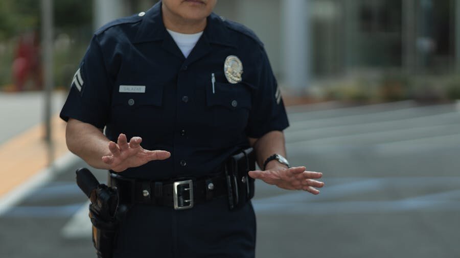 Un officier de police en uniforme se tient à l’extérieur, levant les mains pour signaler un arrêt.